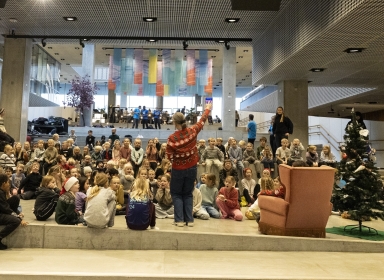 Billede af en kvinde, der på en scenen foran en masse mennesker
